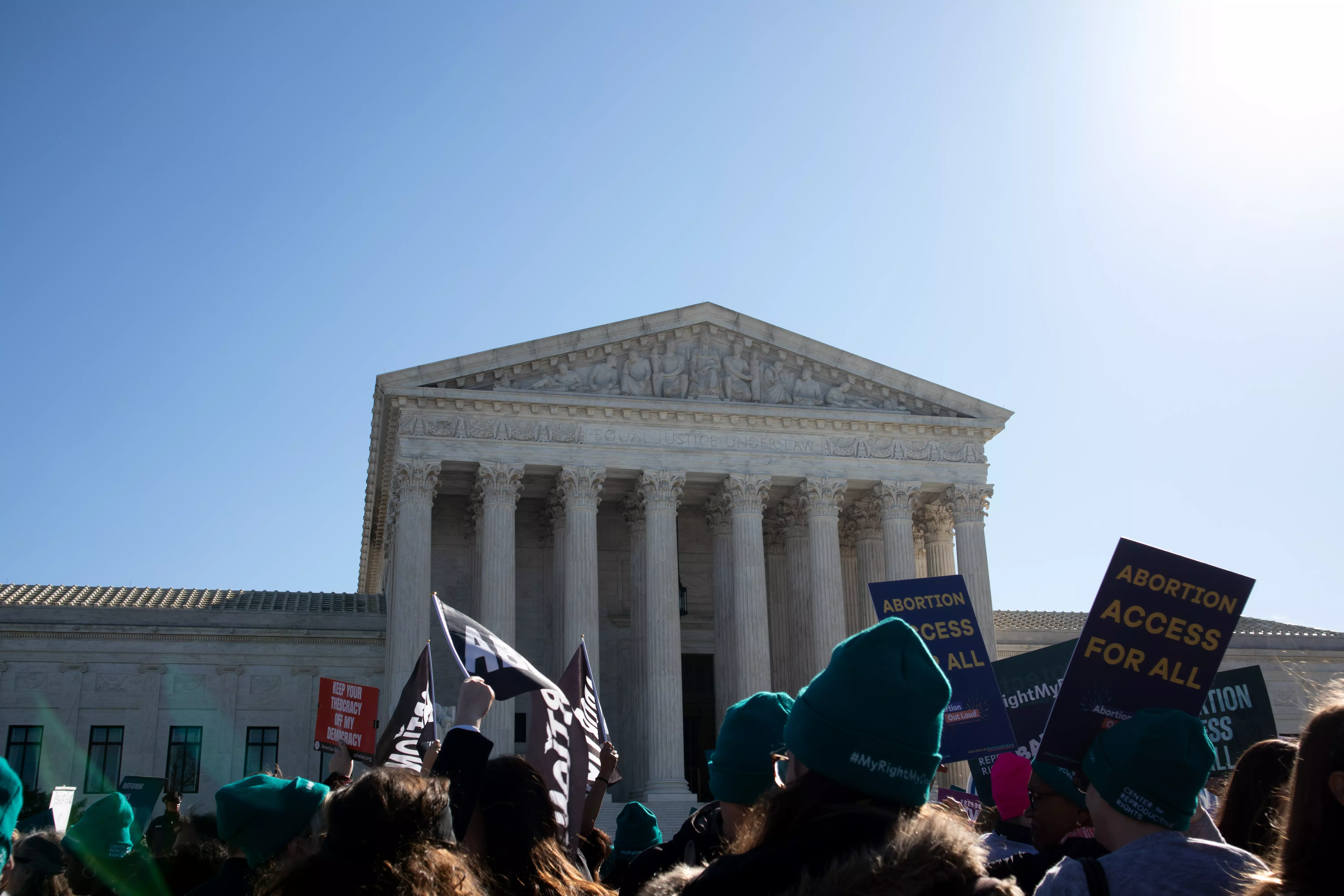 A wide shot of the US Supreme Court building with dozens of protestors in front, with both pro- and anti-choice signs.